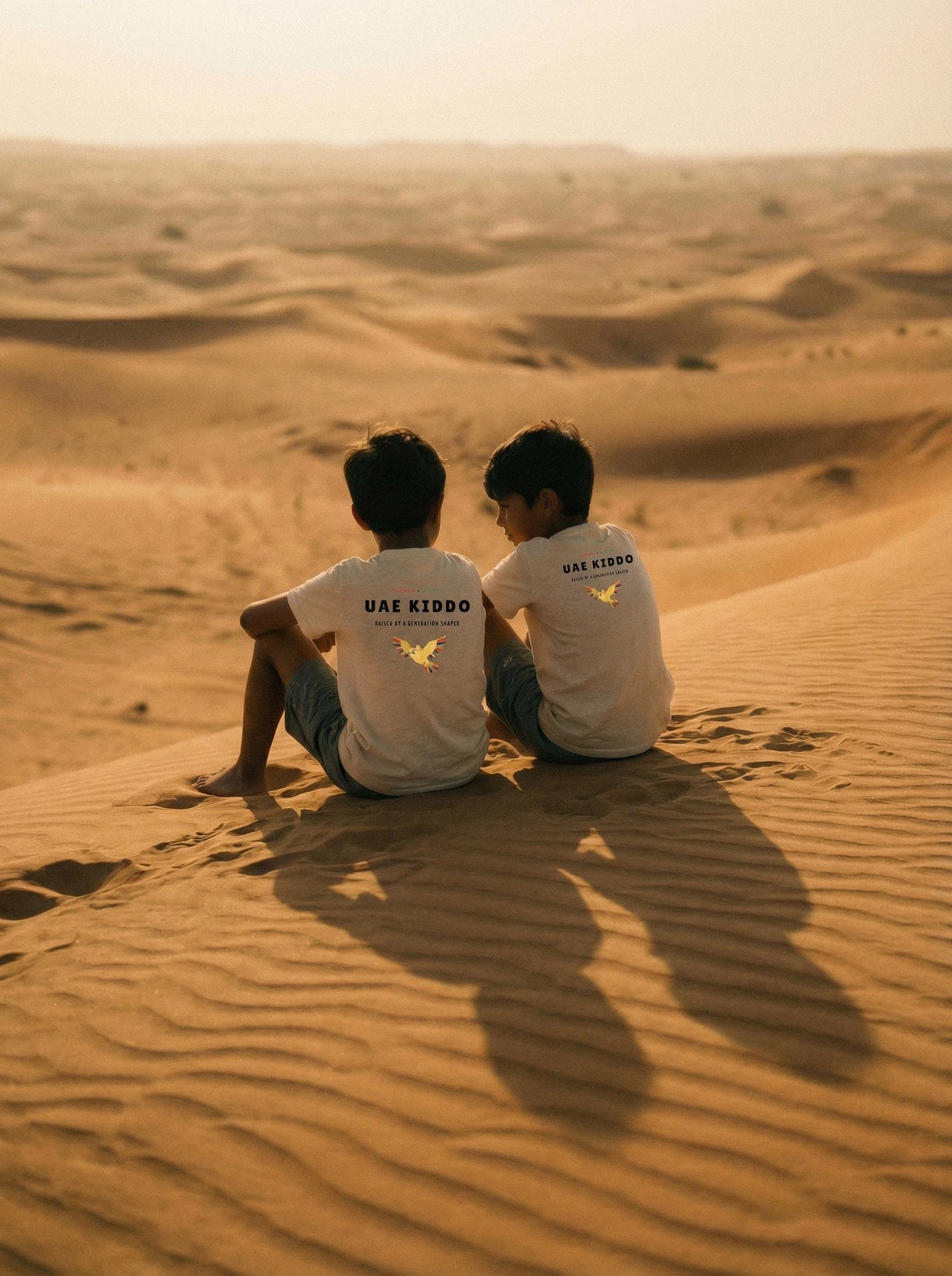 Two brothers in UAE Kiddo t-shirts watching the desert sunset